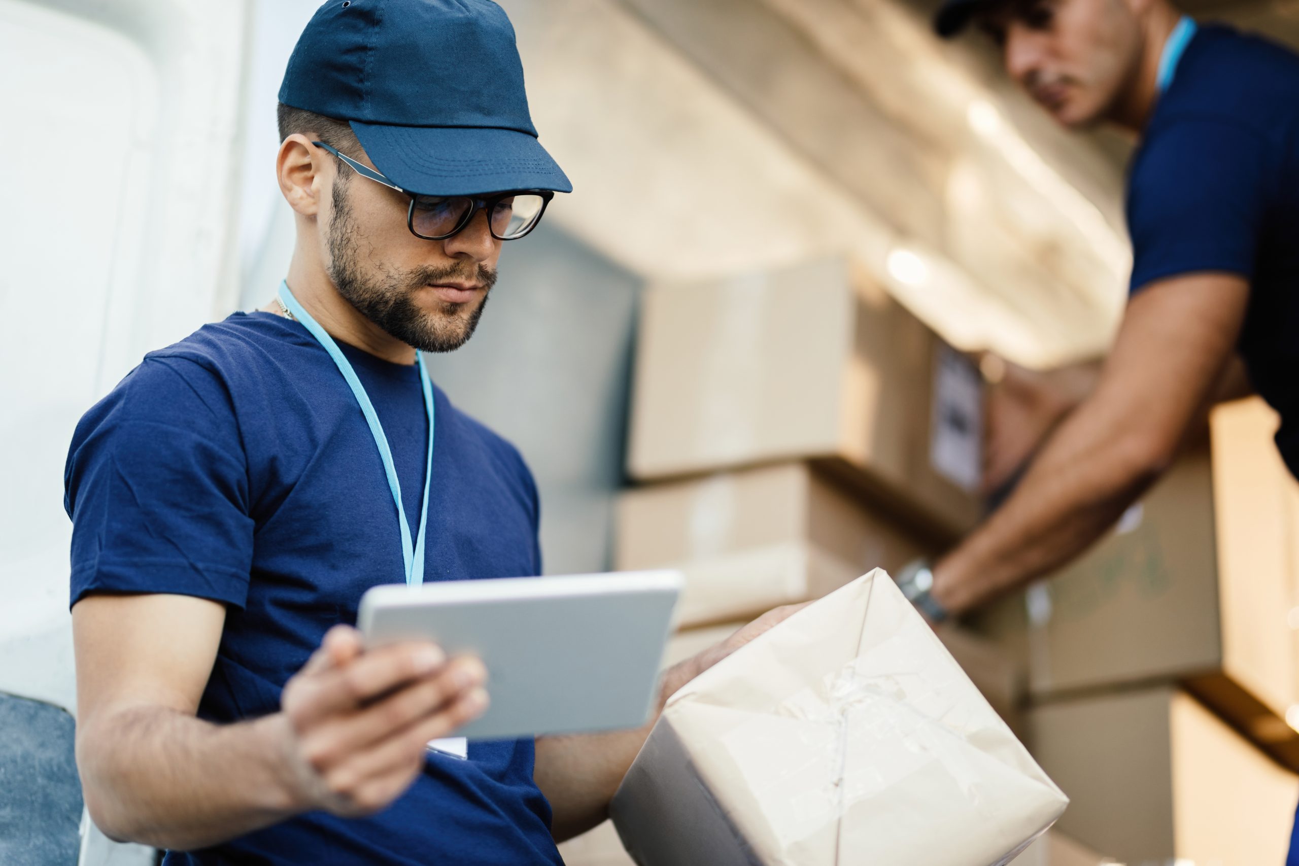 young-delivery-man-using-touchpad-while-reading-label-package.jpg